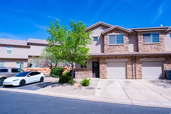 View of front of property with stucco siding, a garage, driveway, and stone siding