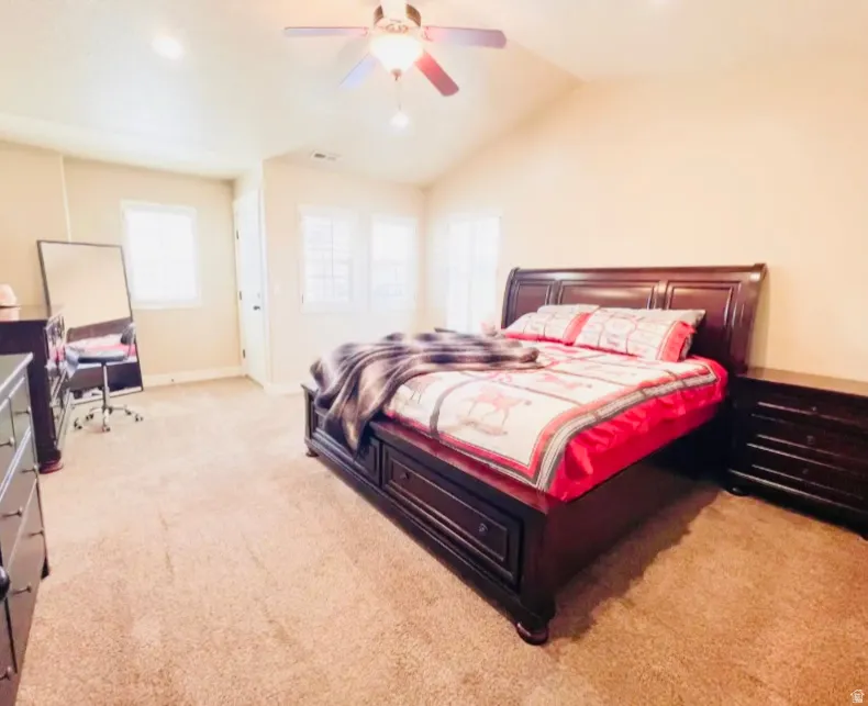 Bedroom with light carpet, a ceiling fan, and lofted ceiling