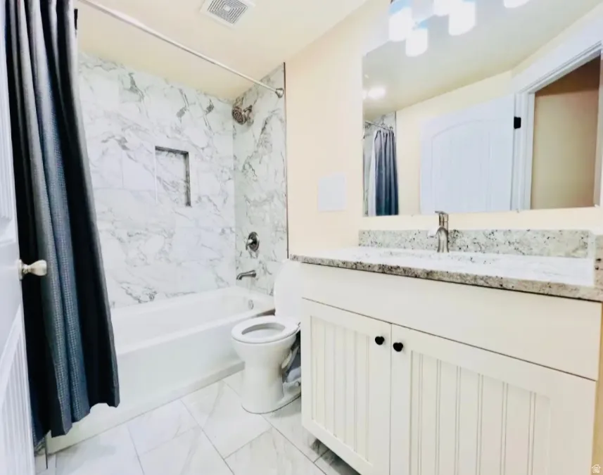 Full bathroom with light marble finish flooring, vanity, and shower / bath combination with curtain