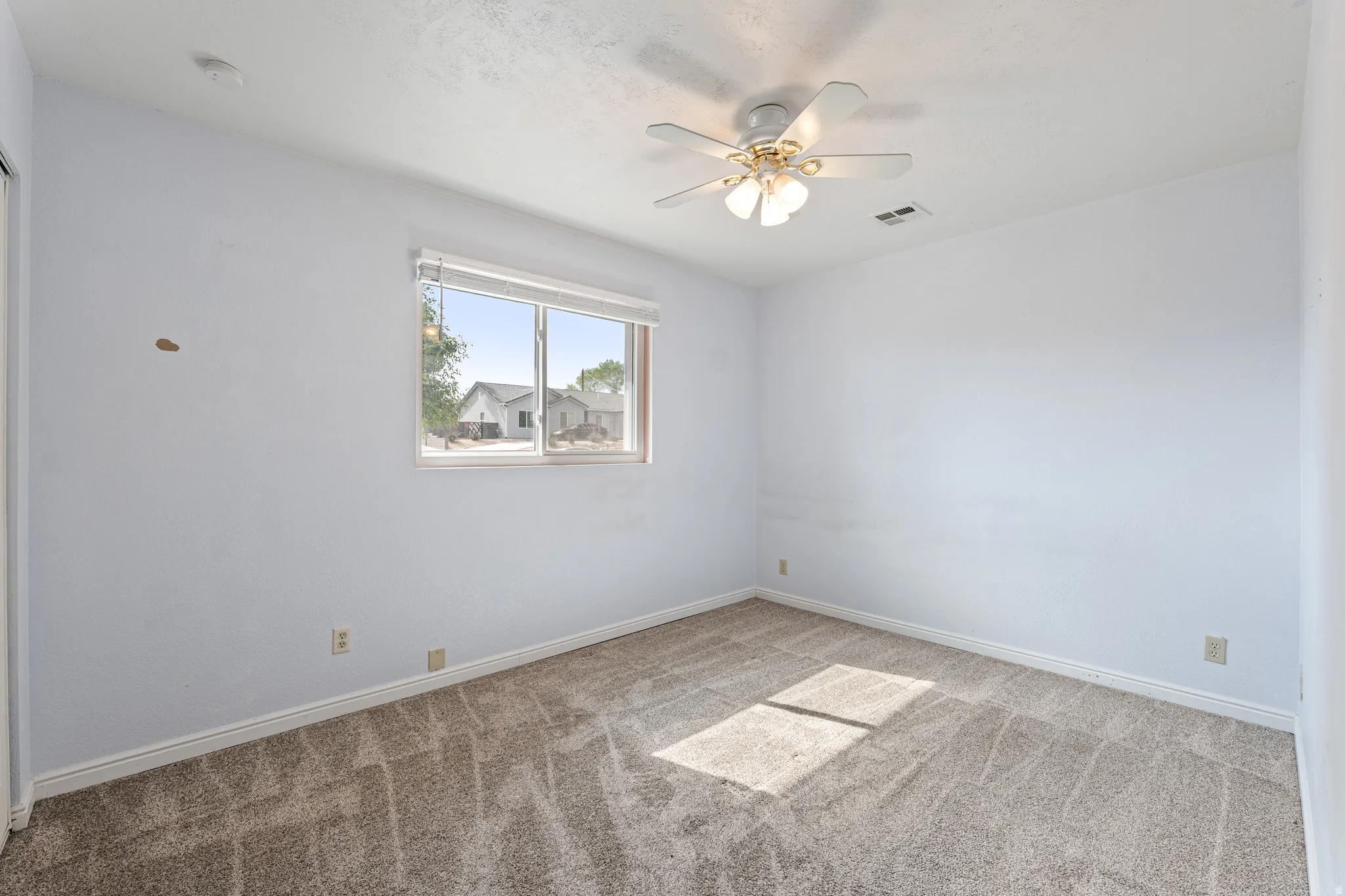 Empty room with light carpet and ceiling fan