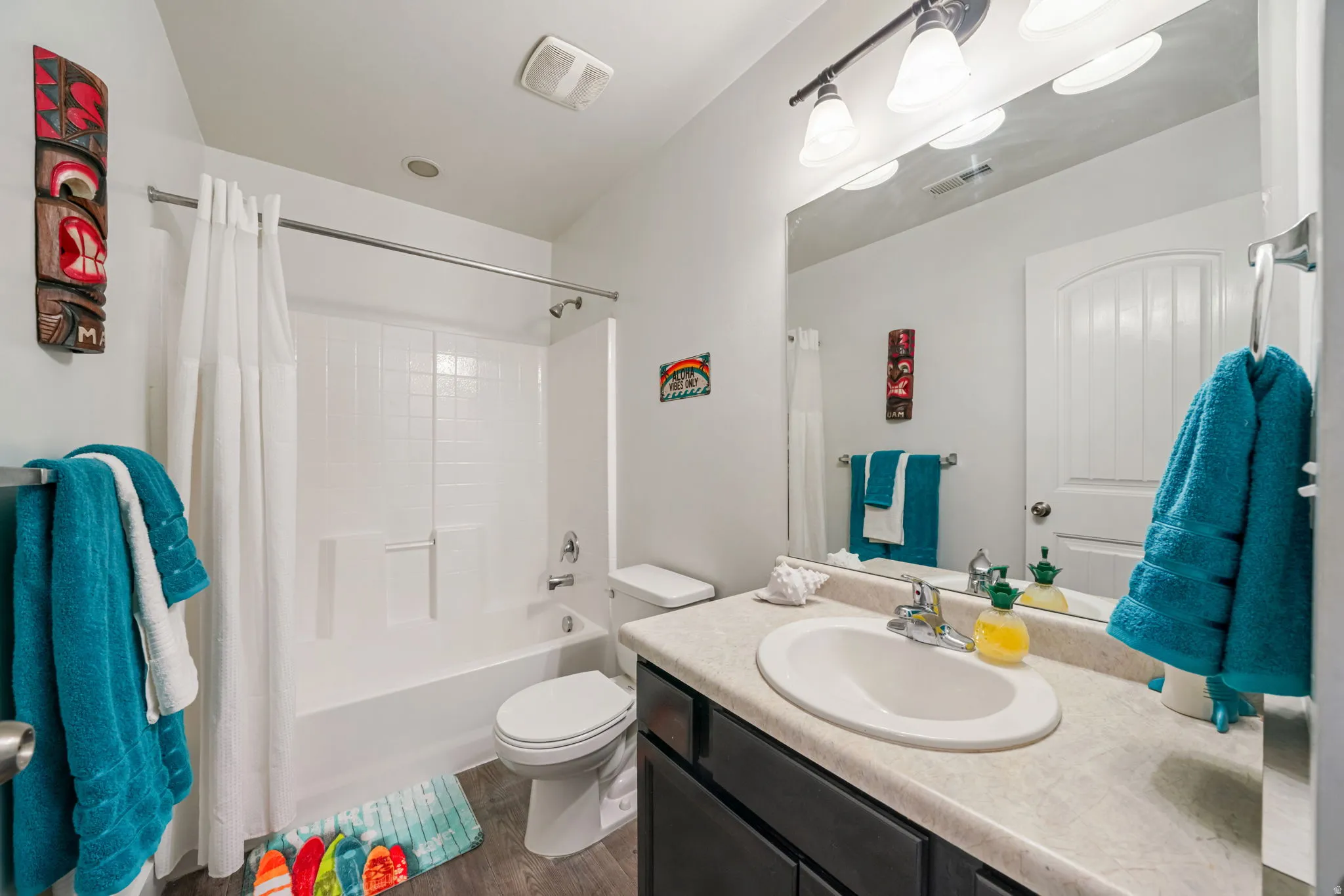 Bathroom with vanity, shower / bathtub combination with curtain, and dark wood finished floors