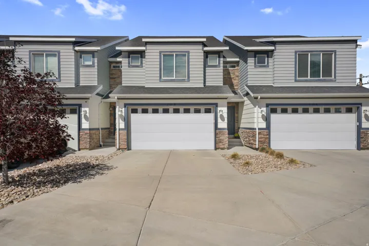 View of front of home featuring stone siding, concrete driveway, a garage, and roof with shingles