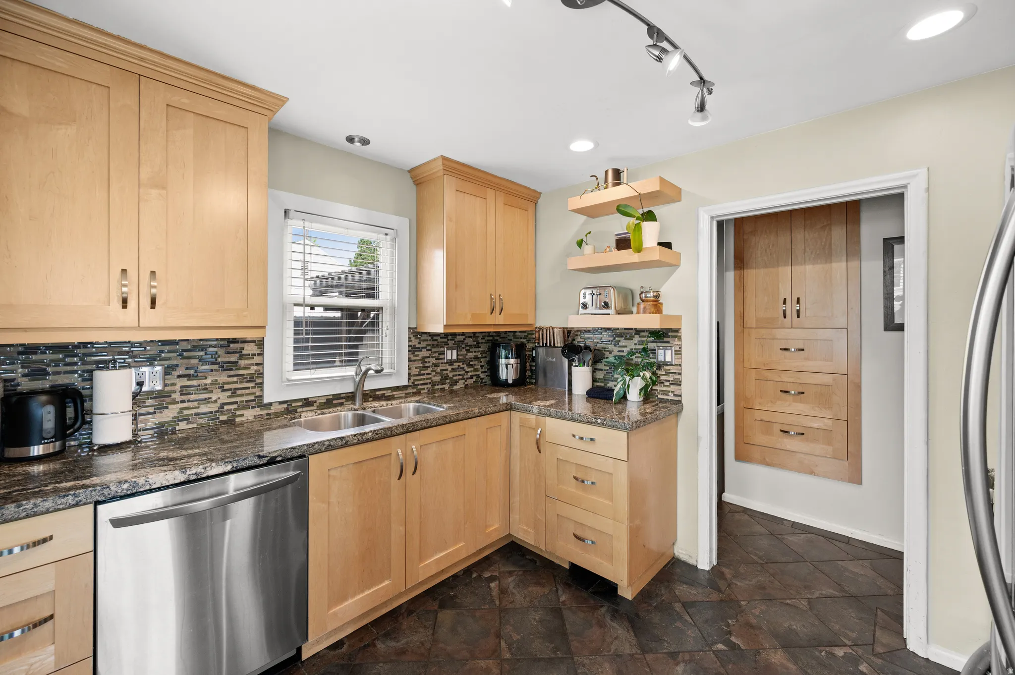 Remodeled Kitchen with light wood finish cabinetry, stainless steel appliances, open shelves, stone finish flooring, and rail lighting