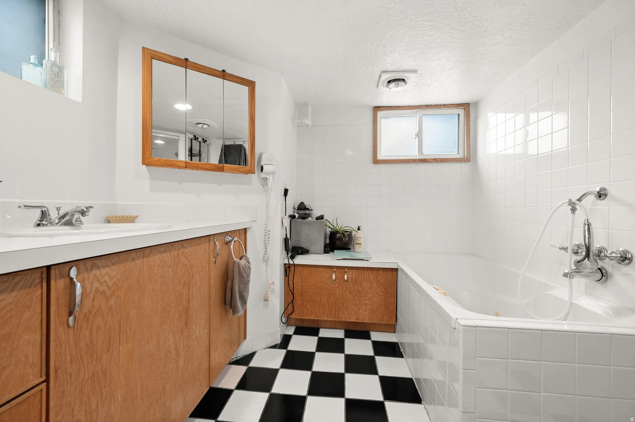 Bathroom featuring vanity, dark flooring, a bath, and a textured ceiling