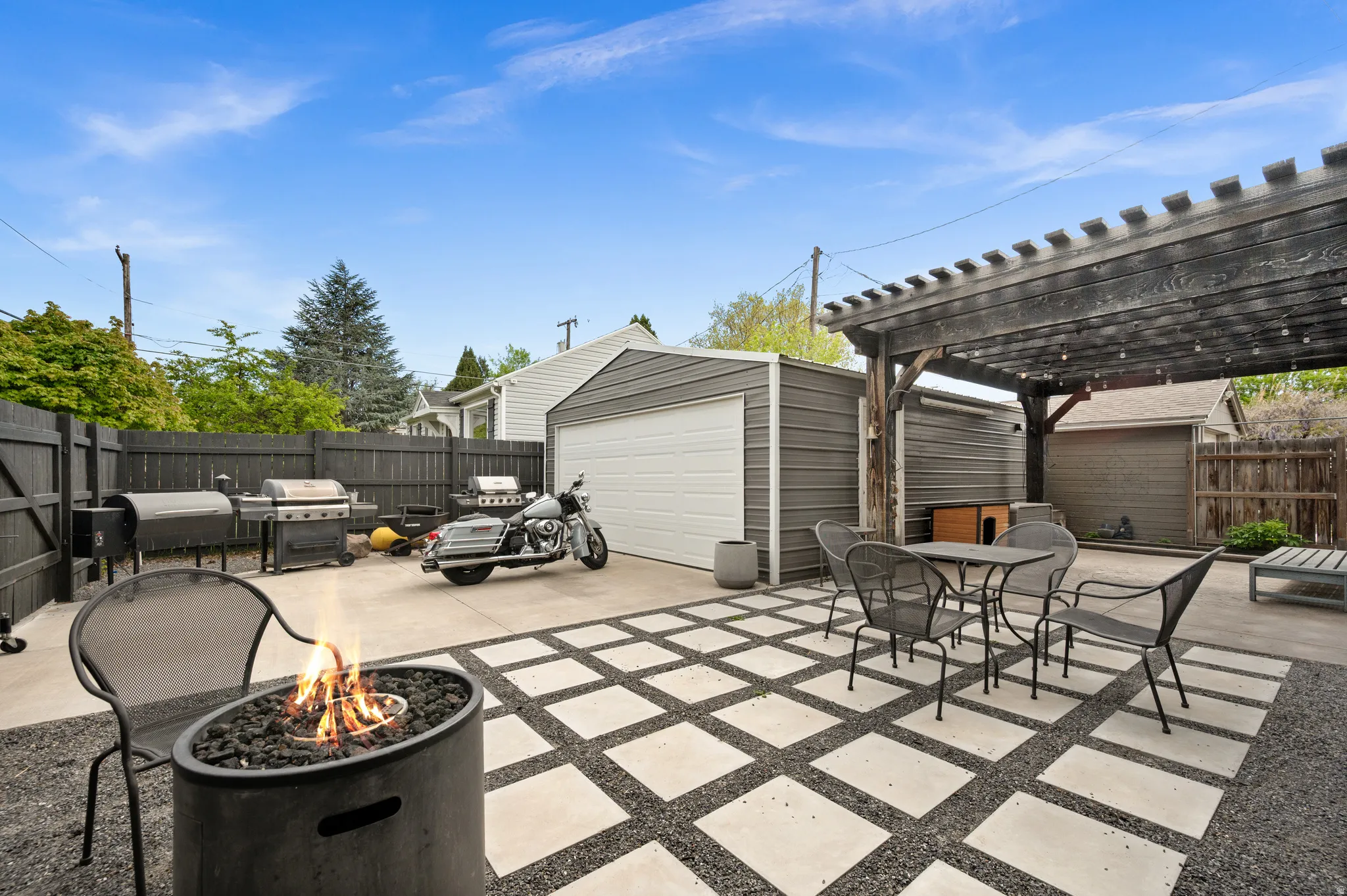 Fenced backyard with a patio, outdoor dining space, grilling area, a garage, and a pergola