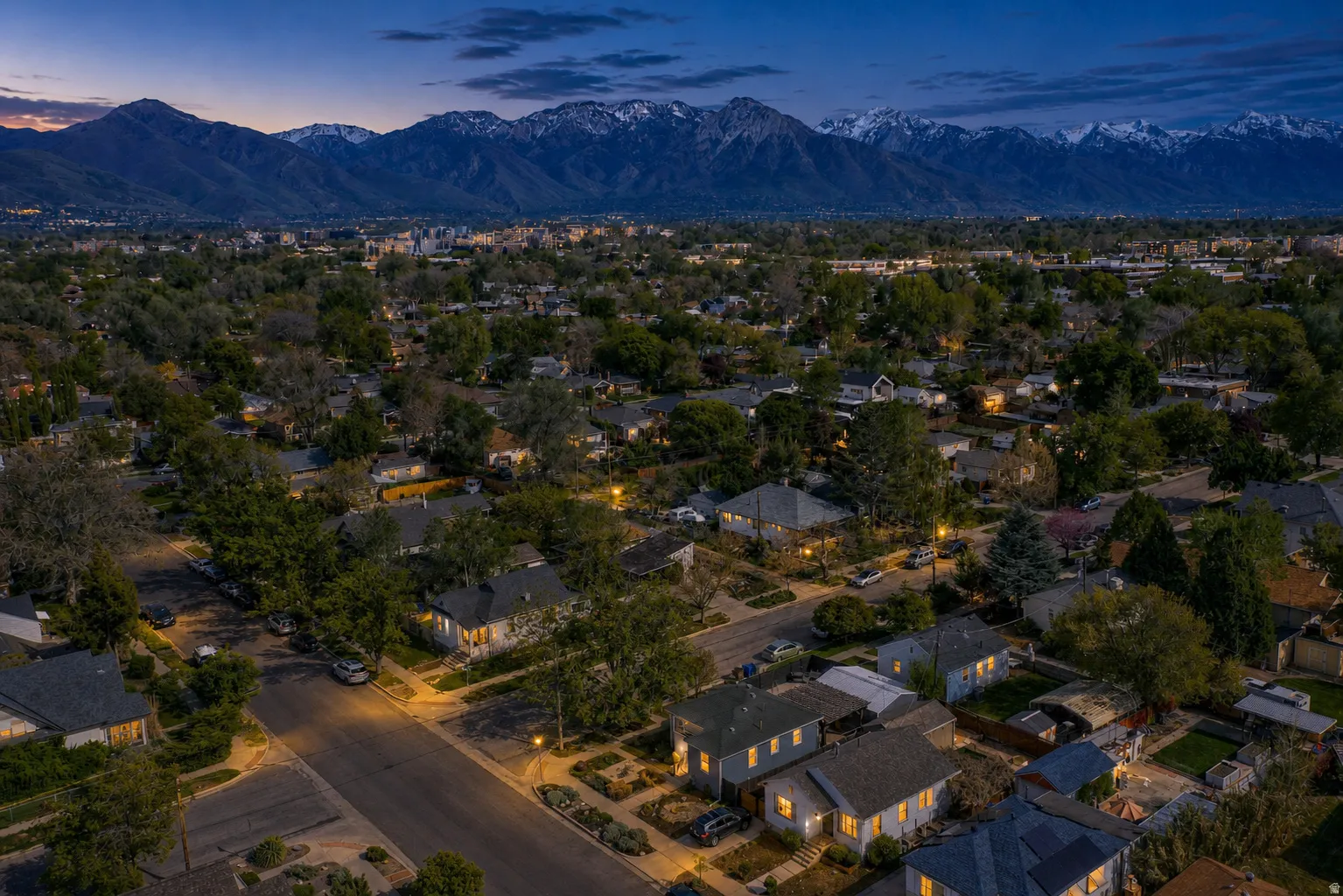 Sprawling neighborhood with mature trees and a prominent mountain range backdrop