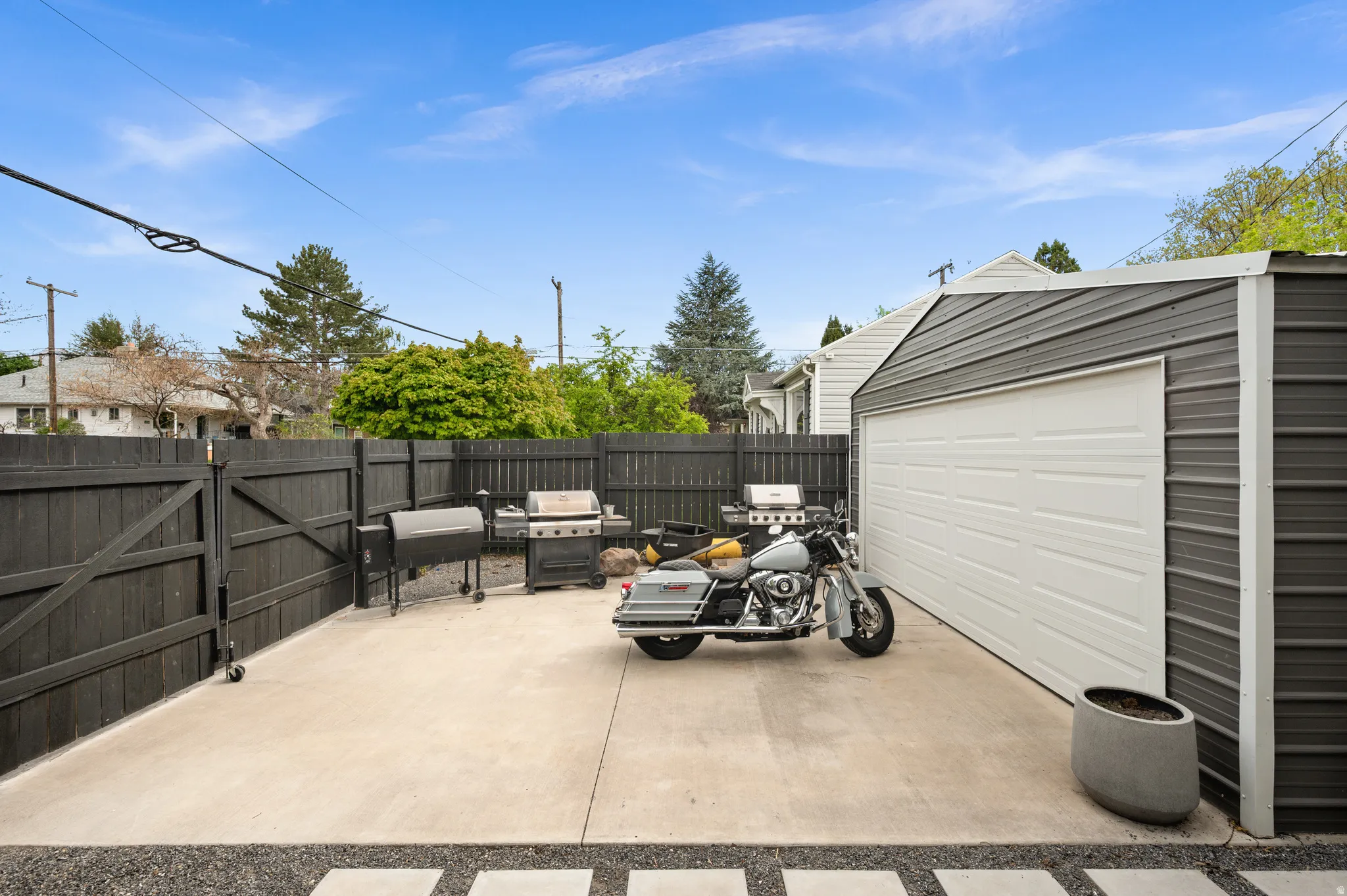 Fenced backyard with area for grilling, a gate, a patio area, an outbuilding, and a garage