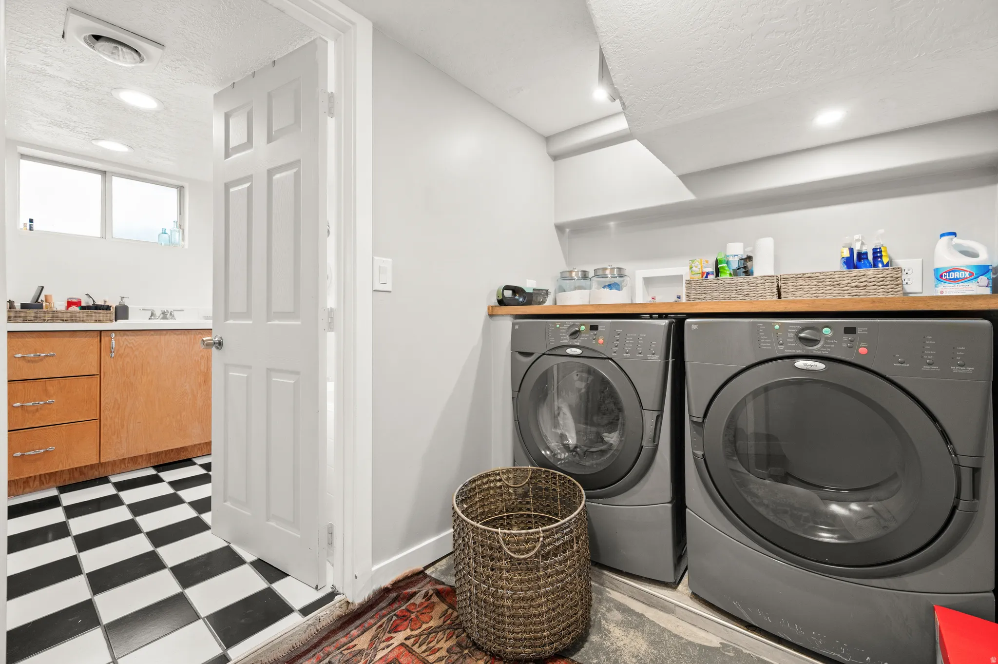 Laundry room with light floors, a textured ceiling, recessed lighting, and washer and clothes dryer