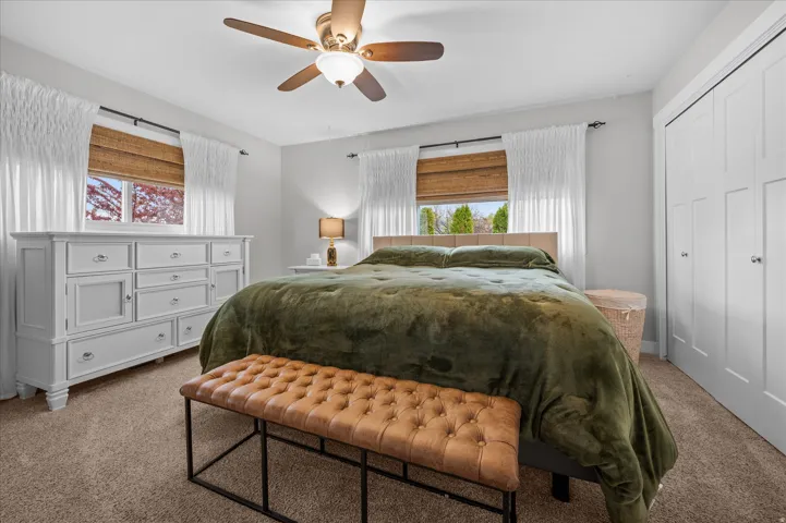 Carpeted bedroom featuring a closet and ceiling fan