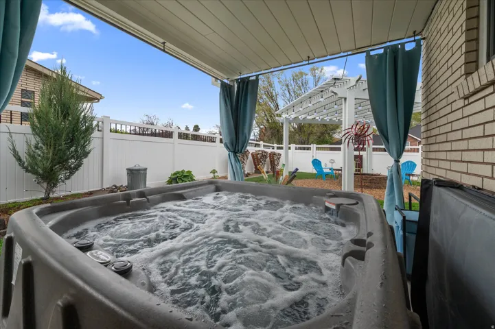 Fenced backyard featuring a hot tub and a pergola
