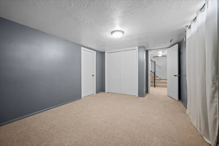 Unfurnished bedroom with a textured ceiling, light carpet, and a closet