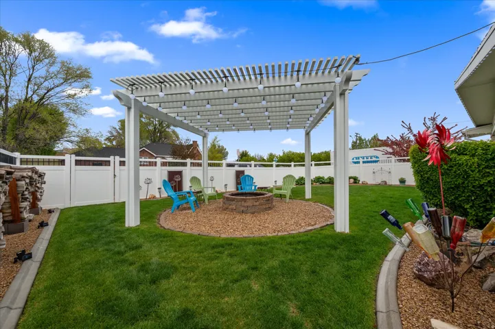 Fenced backyard with a pergola, an outdoor fire pit, and a patio