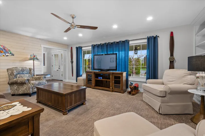 Living room with wood walls, recessed lighting, ceiling fan, and carpet floors