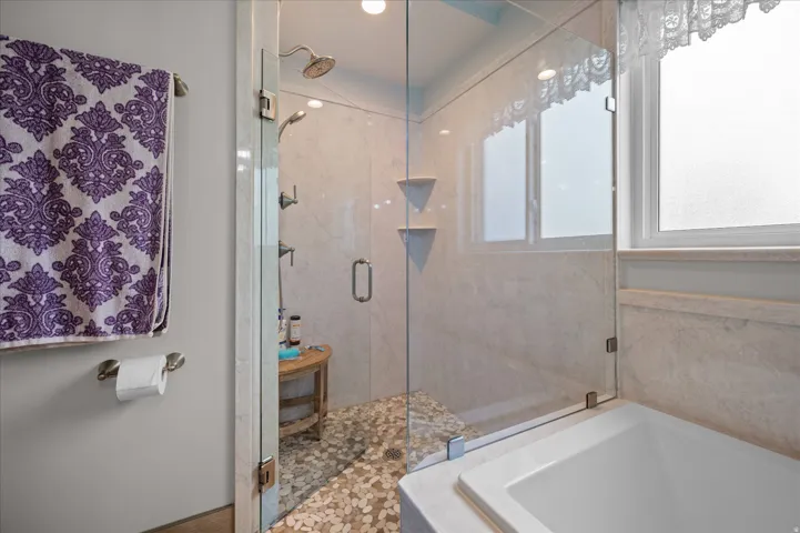 Bathroom featuring a marble finish shower and a bath