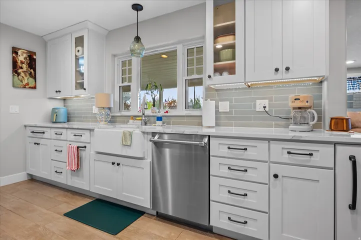 Custom kitchen featuring glass insert cabinets, white cabinets, and healthy amount of natural light