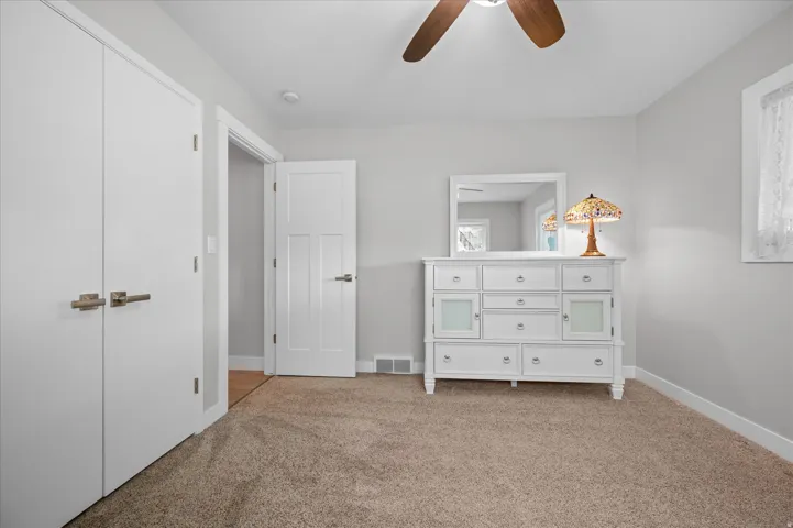 Bedroom with light colored carpet and ceiling fan