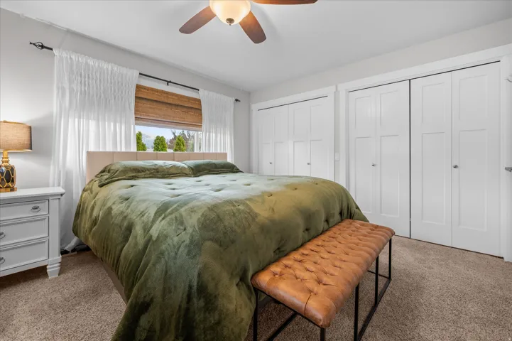 Bedroom featuring two closets, carpet floors, and a ceiling fan