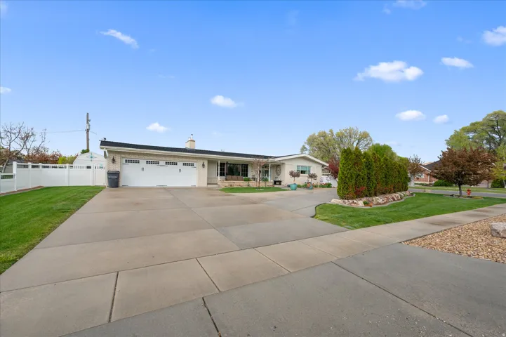 Single story home with driveway, a garage, a chimney, and brick siding