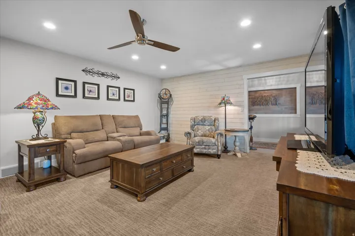Living area with wooden walls, recessed lighting, ceiling fan, and carpet flooring