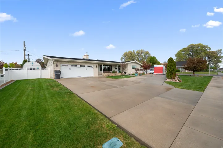 Single story home with a garage, a chimney, driveway, brick siding, and a gate