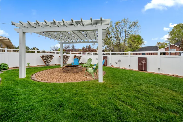 Fenced backyard featuring a pergola and a fire pit