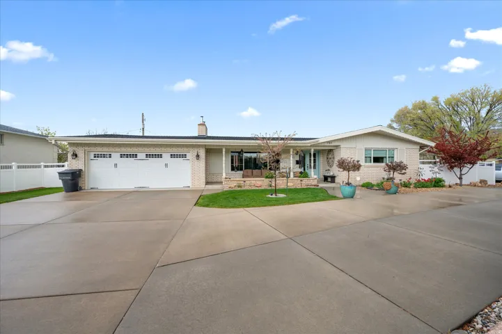 Ranch-style home with driveway, an attached garage, brick siding, and a chimney
