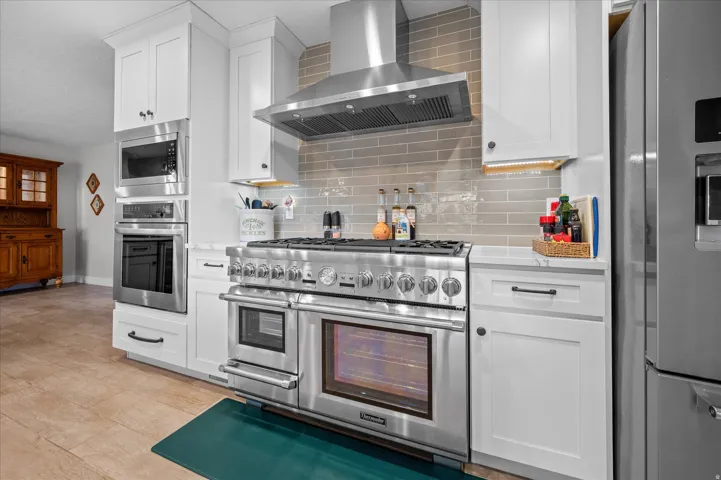 High-end kitchen featuring a 48" Thermador gas range with double ovens, wall ovens, refrigerator. Appliances included.