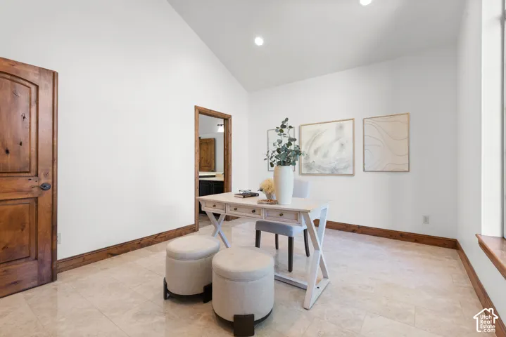Spacious room featuring vaulted ceilings, recessed lighting, wood-finish doors and trim, tile flooring, and a large window