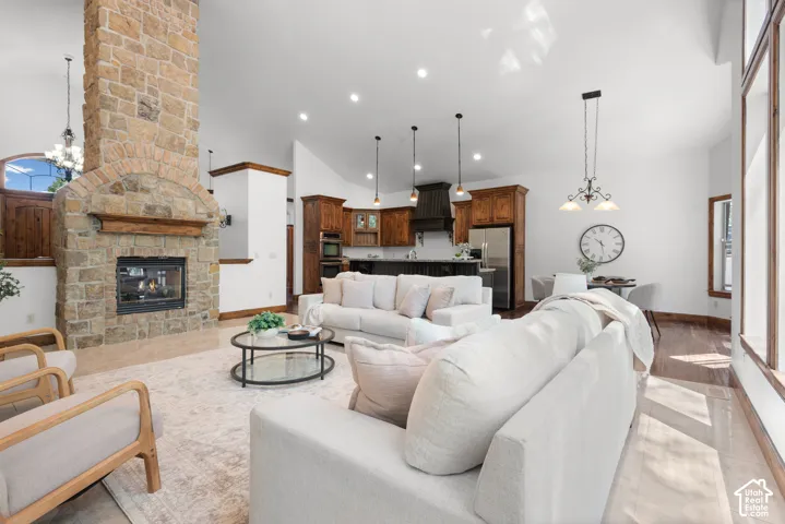 Expansive living area featuring a floor-to-ceiling stone fireplace, vaulted ceilings, natural wood-finish flooring, and large windows