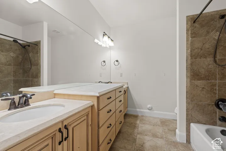 Full bath with tiled shower / bath and double vanity