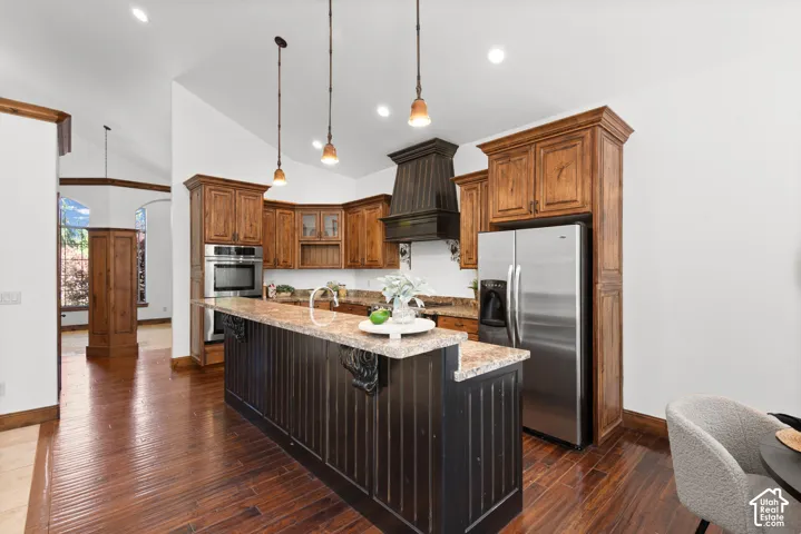 Kitchen featuring wood-finish flooring, a central island with a multi-tone countertop, and stainless steel appliances