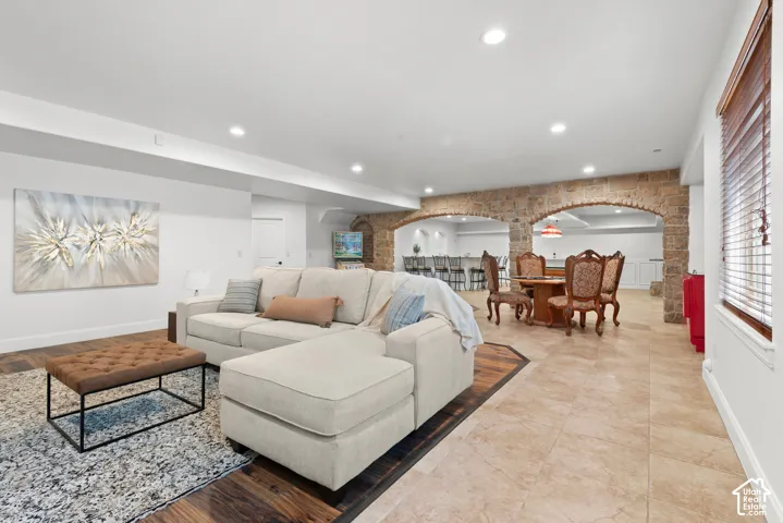 Spacious lower-level living area with recessed lighting and a mix of wood-finish flooring and light-toned tile