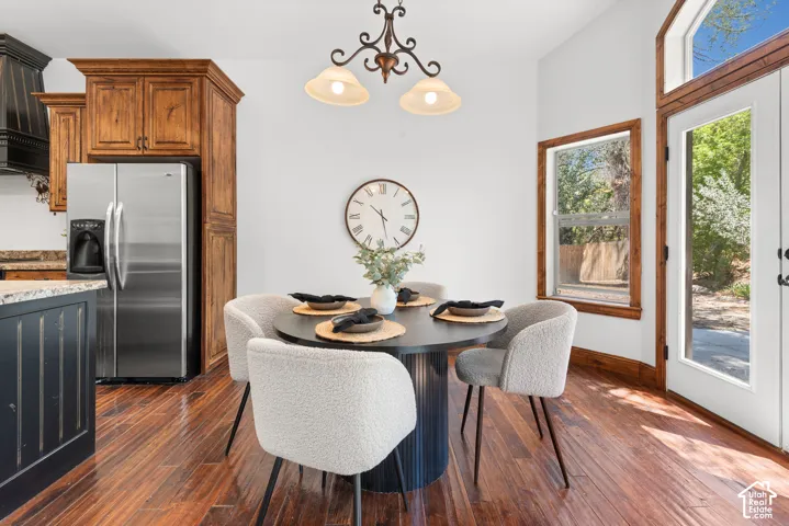 Dining area featuring rich wood-finish flooring, white walls, and a decorative chandelier
