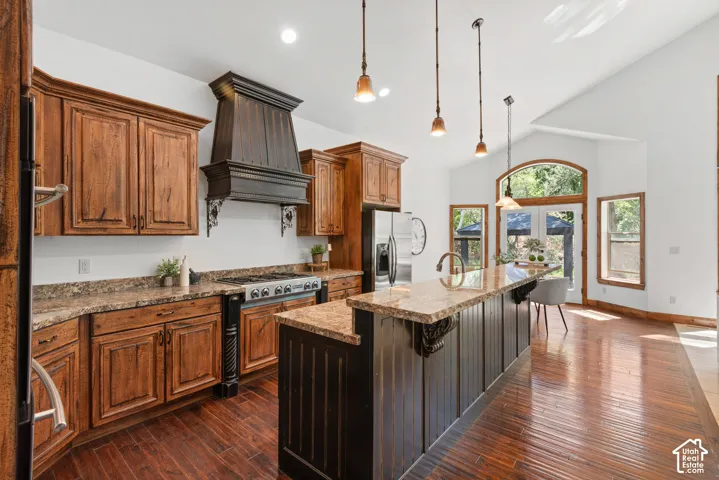 Spacious kitchen featuring rich wood cabinetry, granite-finish countertops, and a custom range hood