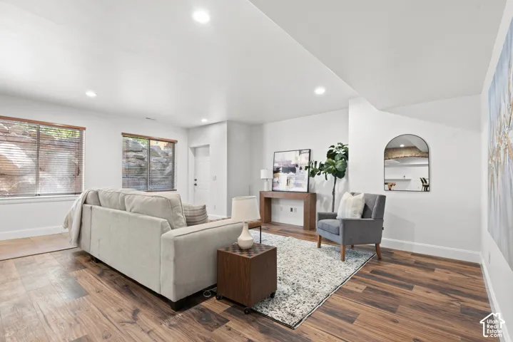 Spacious living area featuring wood-finish flooring, recessed lighting, white walls, and multiple windows