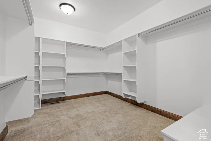 Walk in closet with light colored carpet