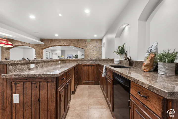 Kitchenette featuring rustic wood cabinetry, stone-finish countertops, tile flooring, and integrated sink with an appliance