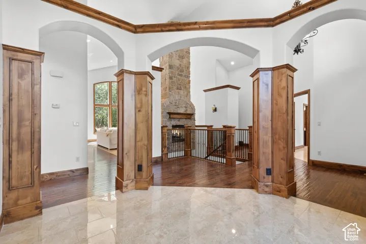 Grand foyer featuring polished tile flooring, wood-paneled columns, and arched doorways
