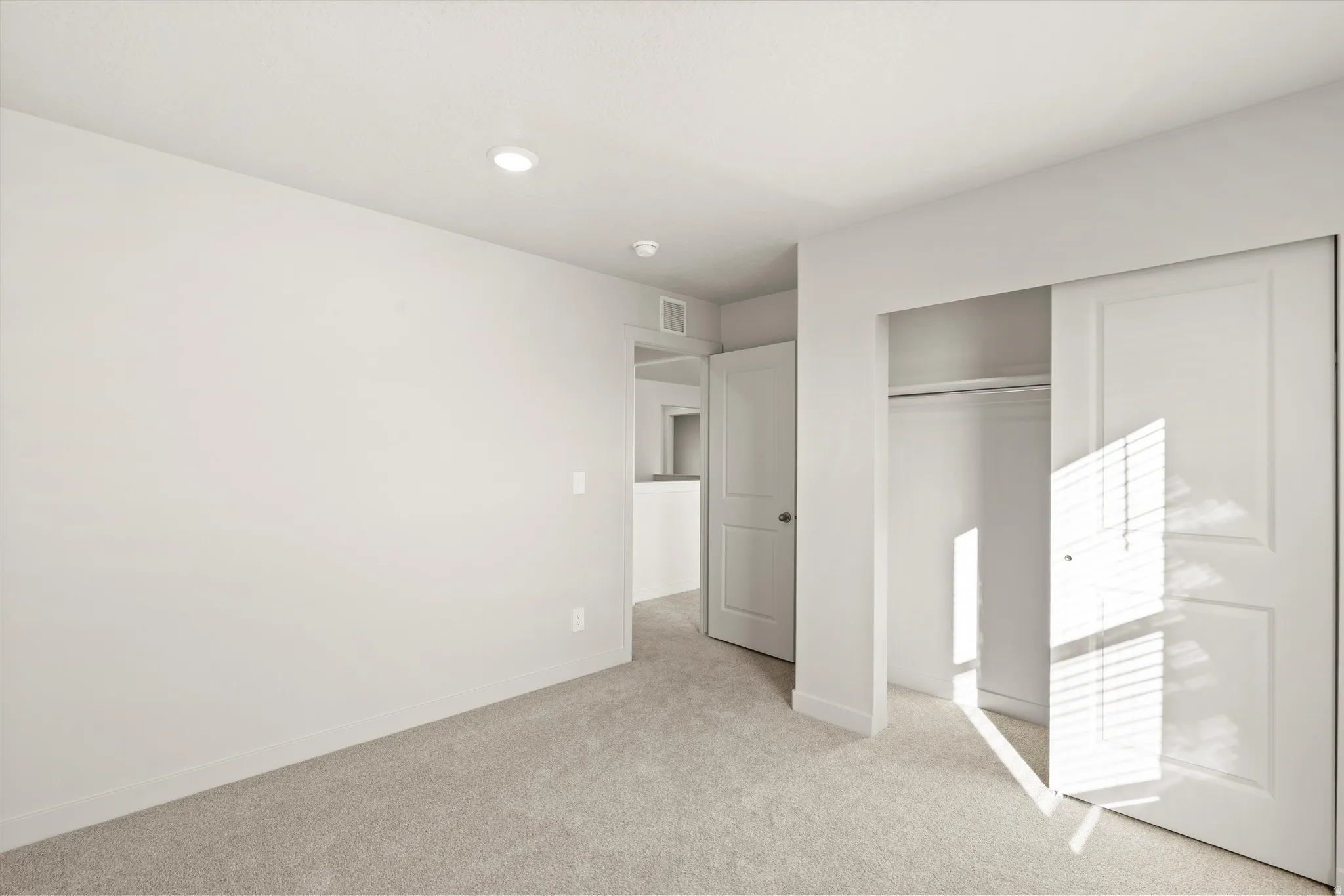 Unfurnished bedroom with light carpet and a closet