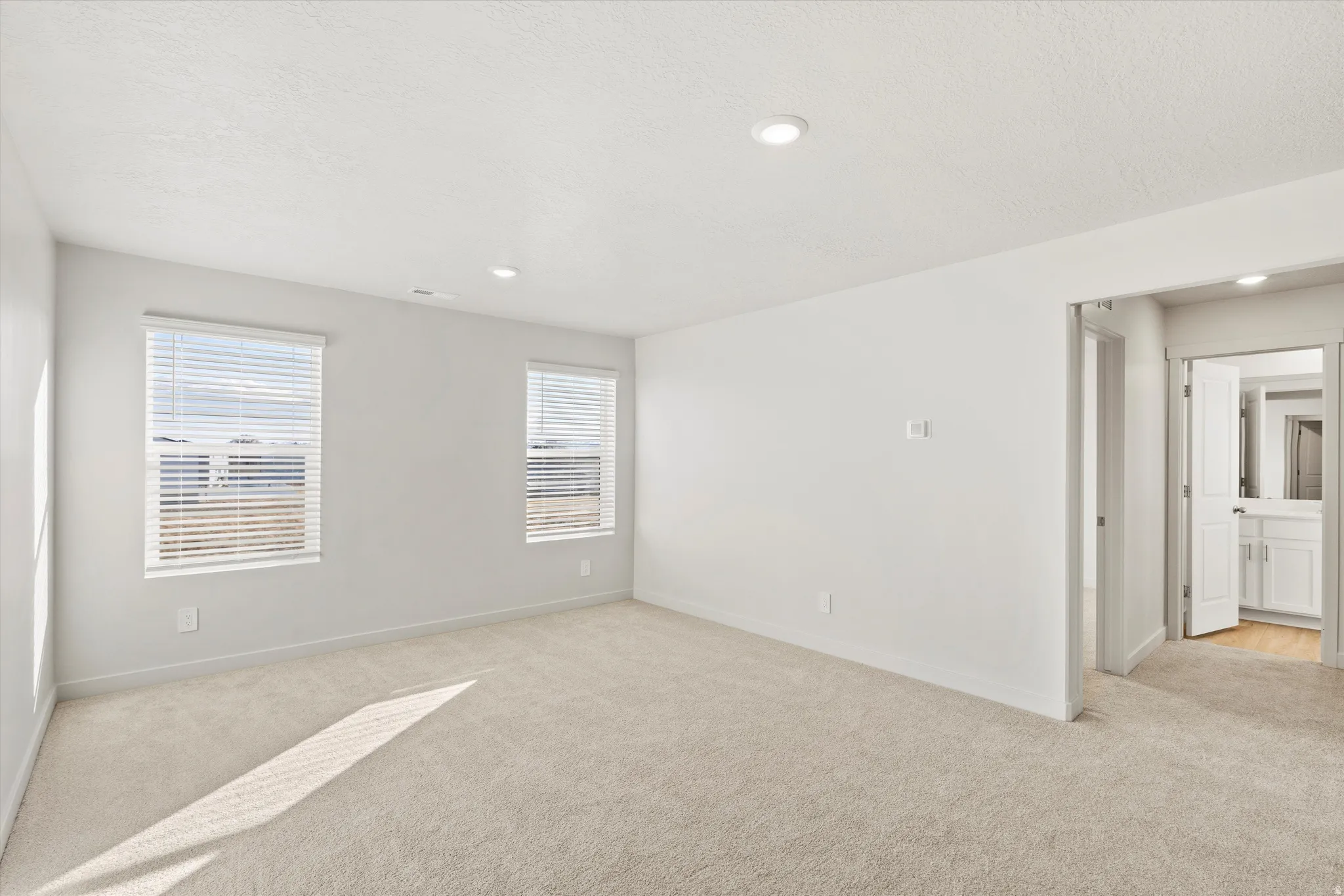 Empty room with light colored carpet, recessed lighting, and a textured ceiling