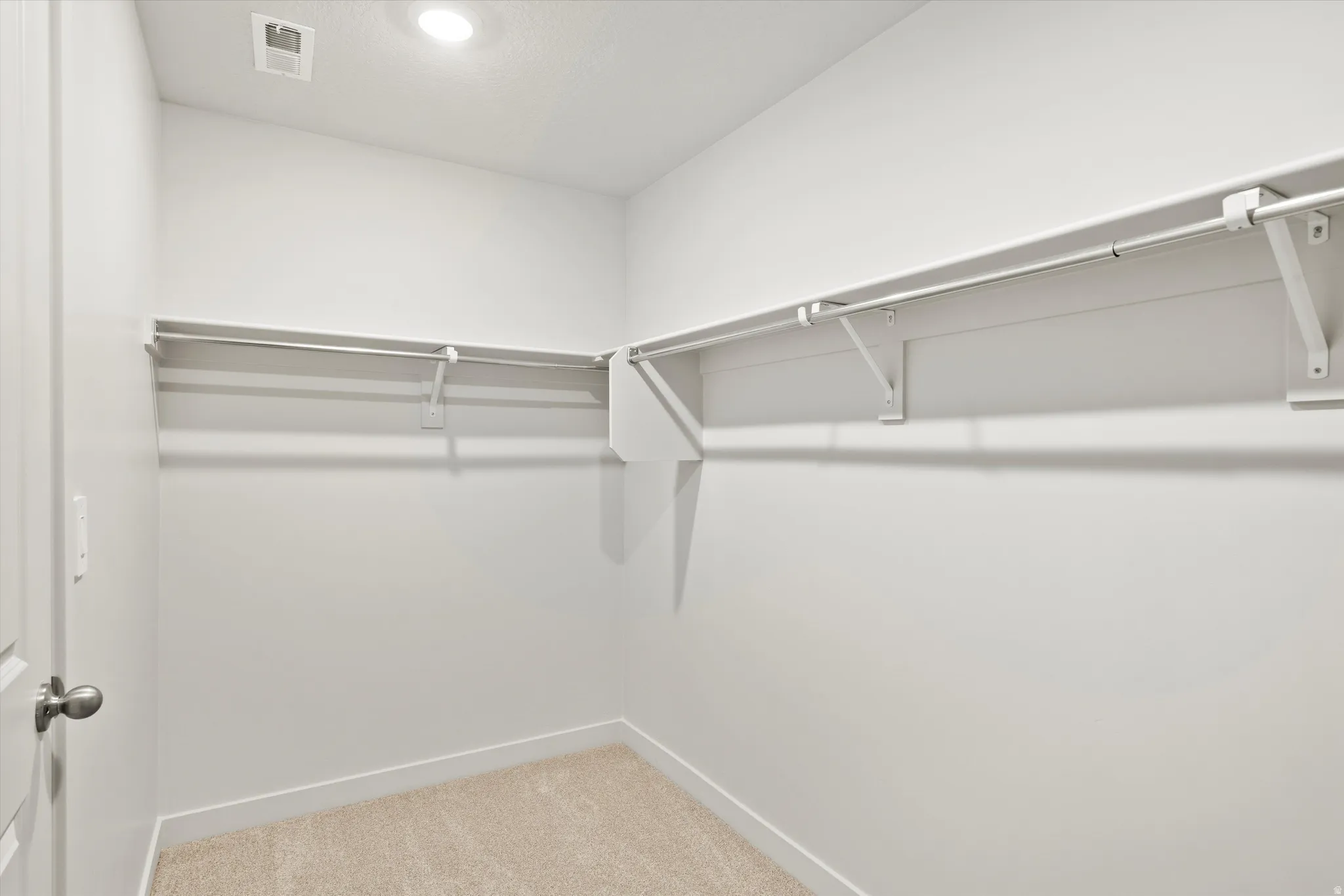 Walk in closet with light colored carpet