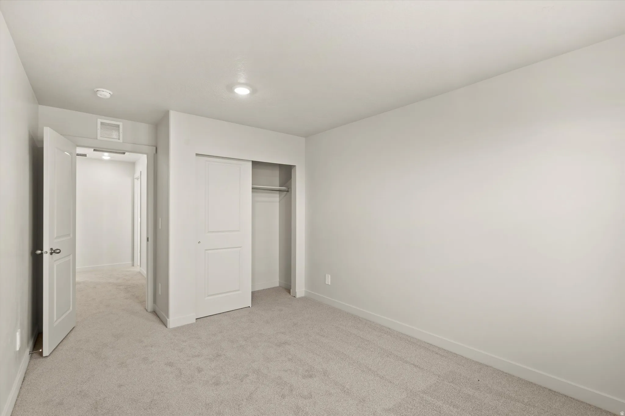 Unfurnished bedroom with light colored carpet and a closet