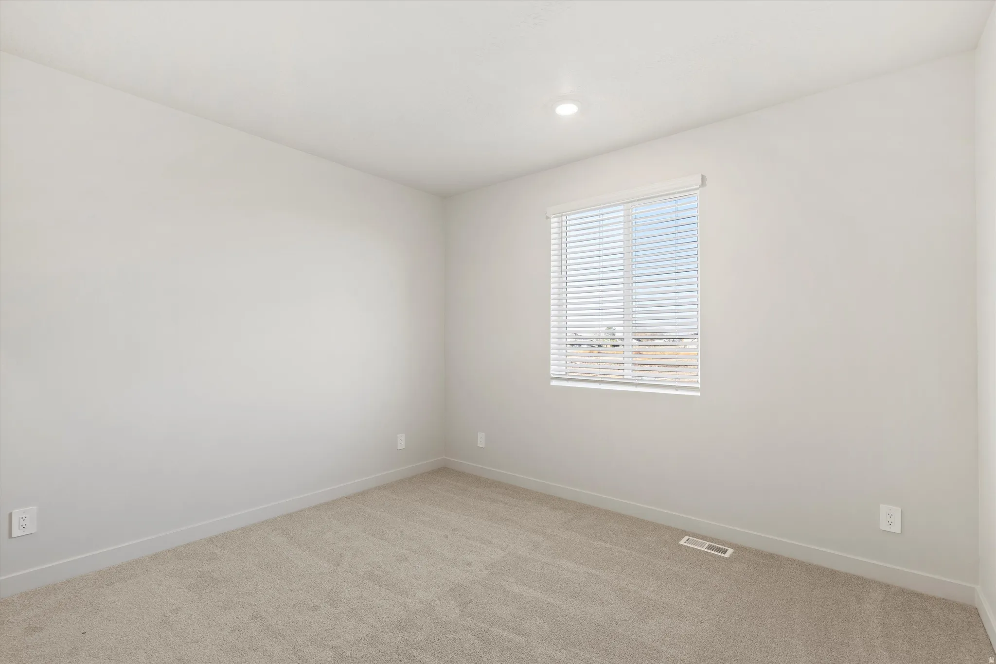 Spare room featuring light carpet and baseboards