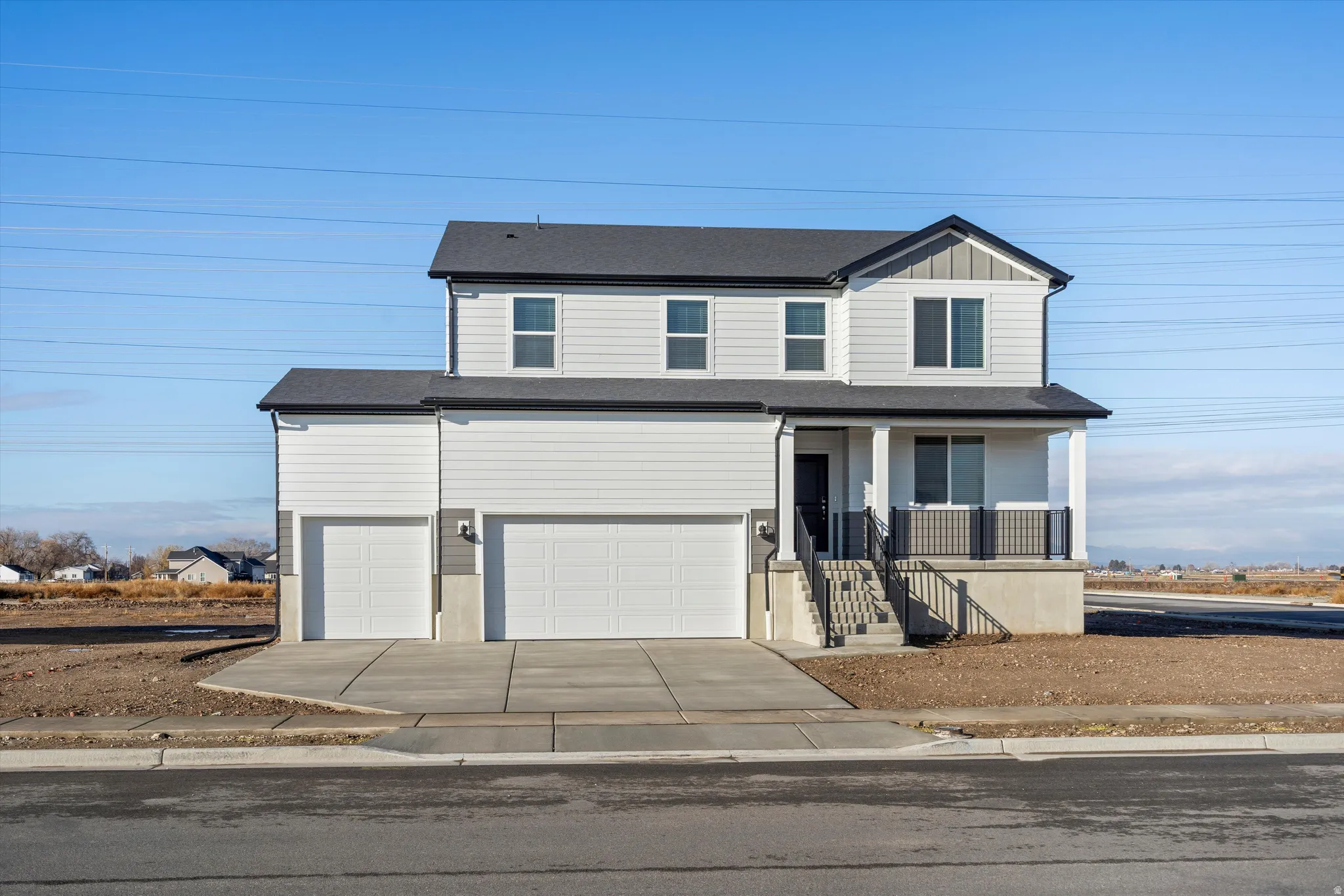View of front of home with covered porch, driveway, an attached garage, and roof with shingles