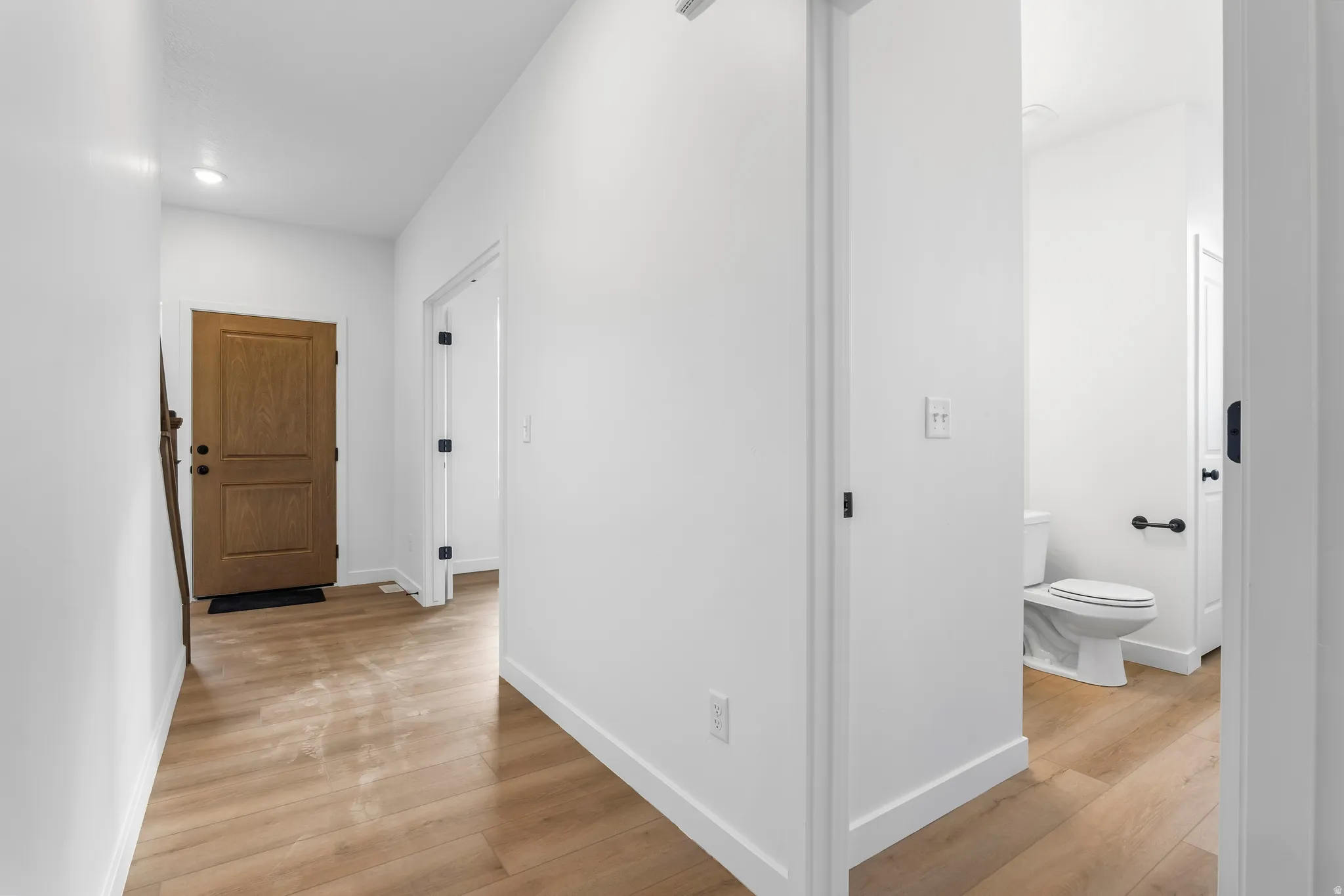 Corridor featuring light wood-style flooring and baseboards