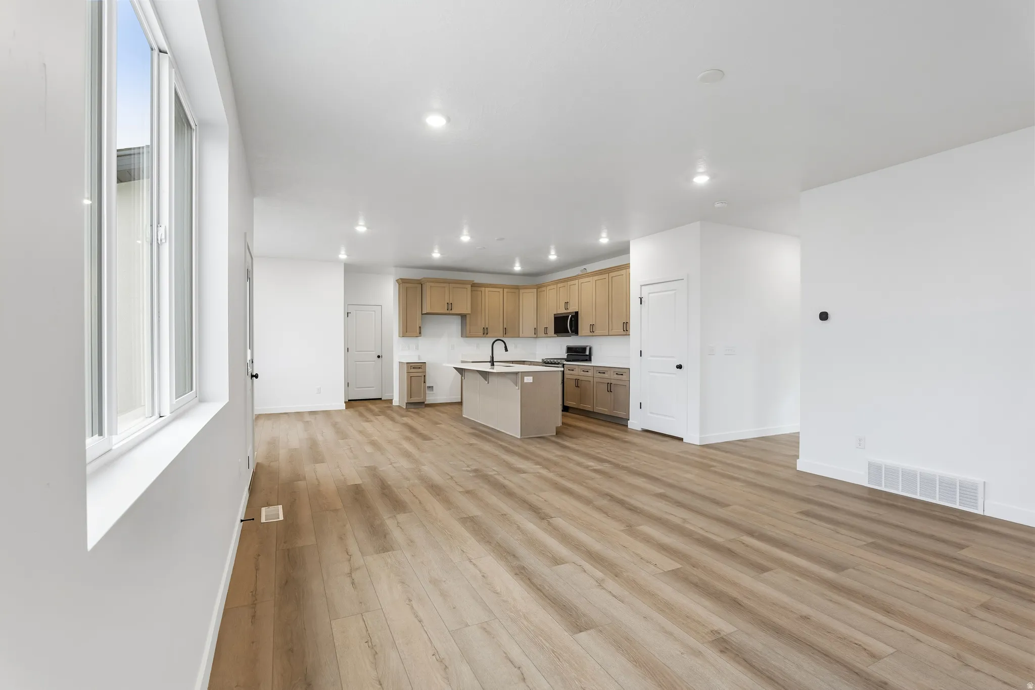 Kitchen featuring open floor plan, an island with sink, a kitchen breakfast bar, light wood-type flooring, and recessed lighting