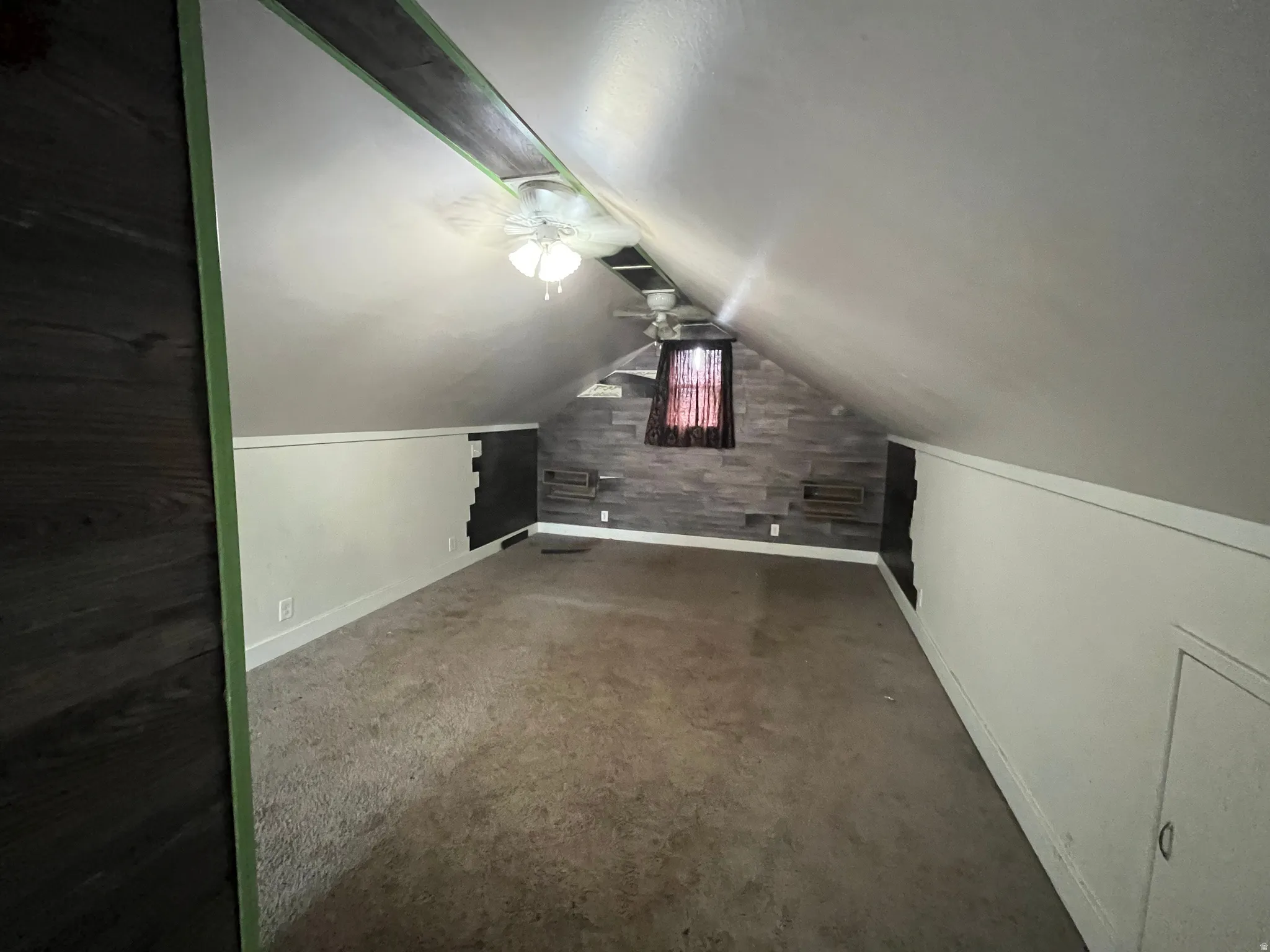 Additional living space featuring a ceiling fan and dark colored carpet