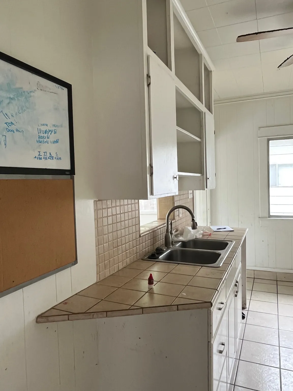 Kitchen featuring tile counters, a ceiling fan, and white cabinets