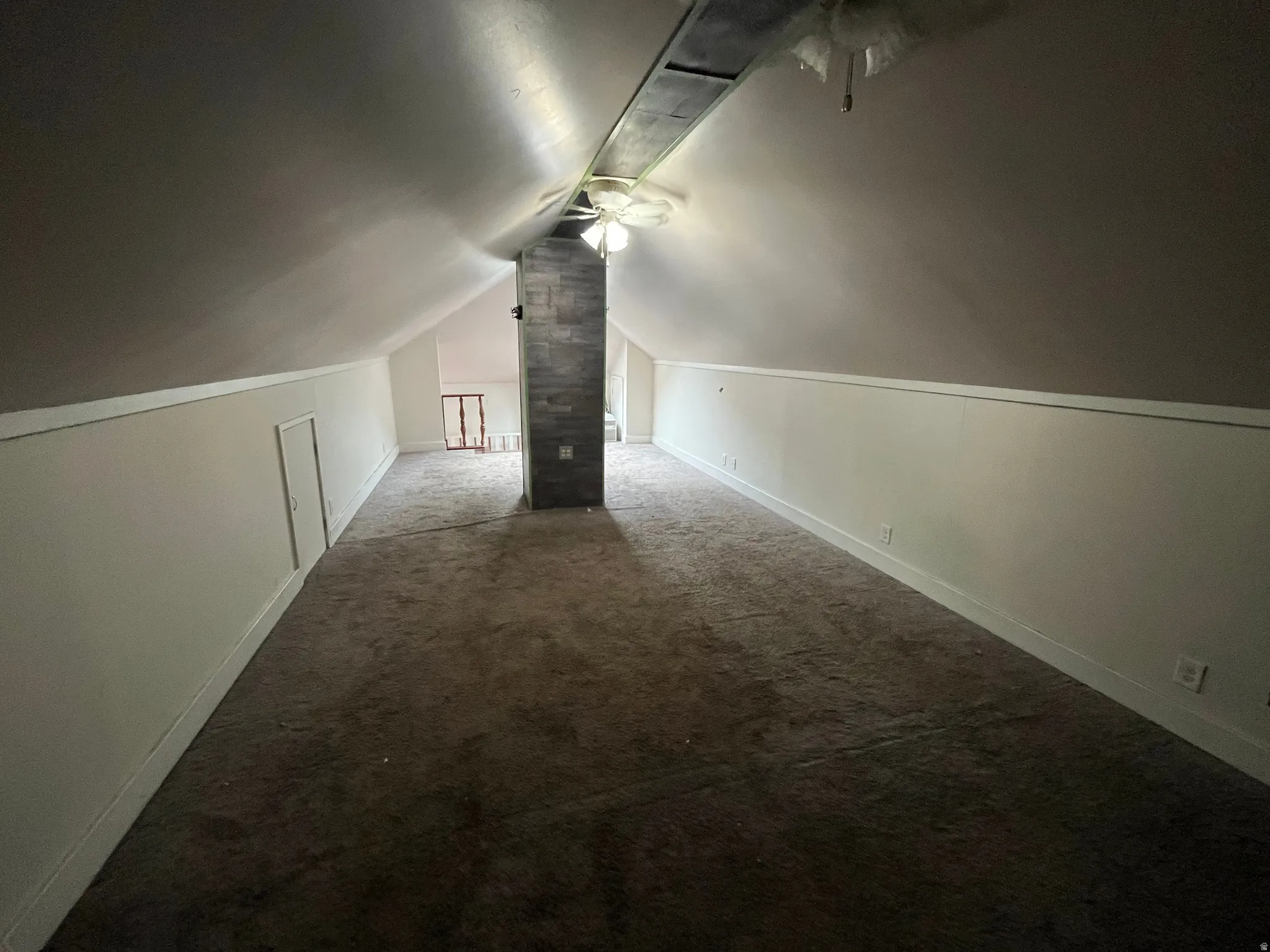 Additional living space featuring dark colored carpet and a ceiling fan