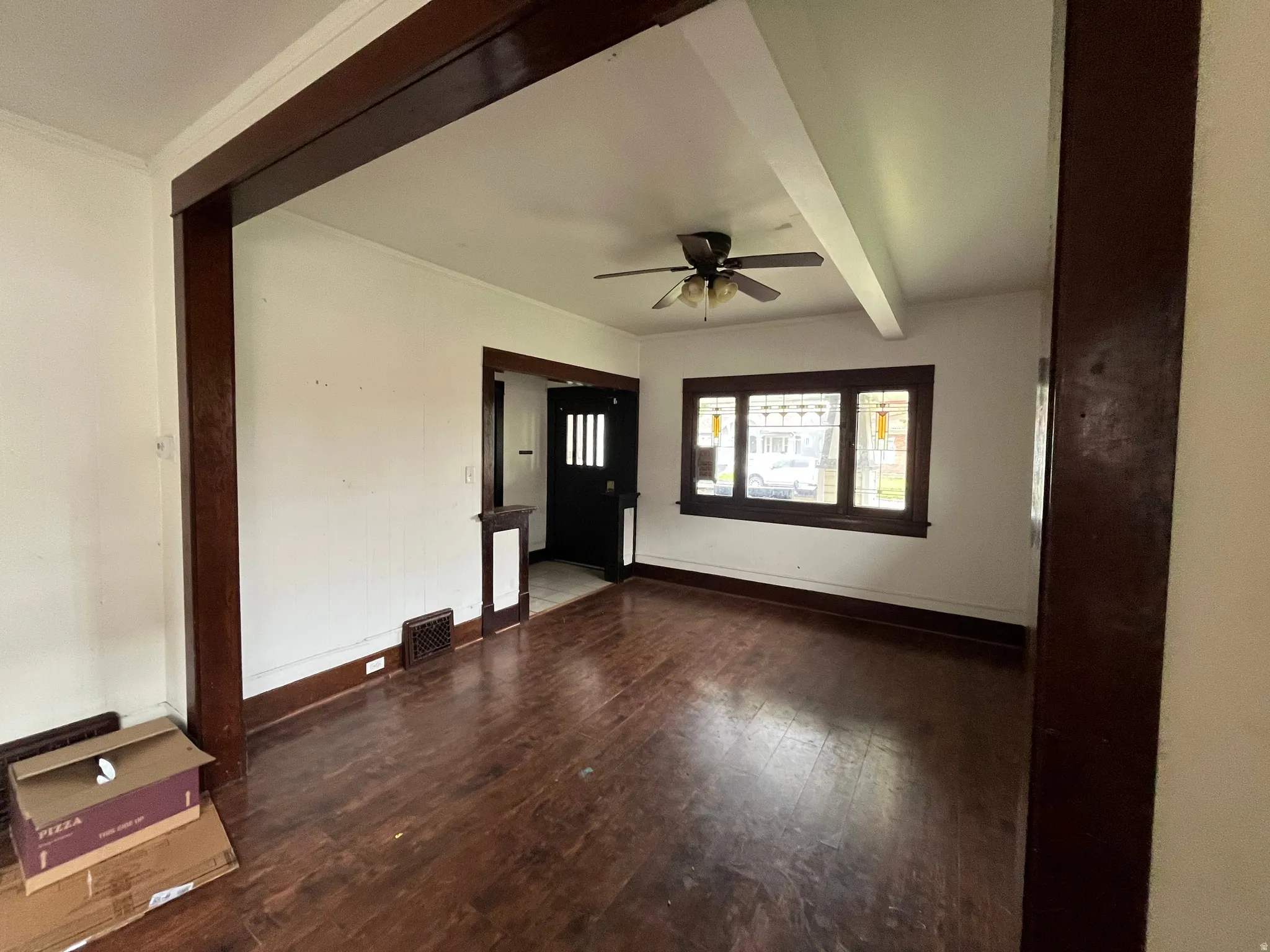 Empty room with dark wood-type flooring, beam ceiling, and a ceiling fan